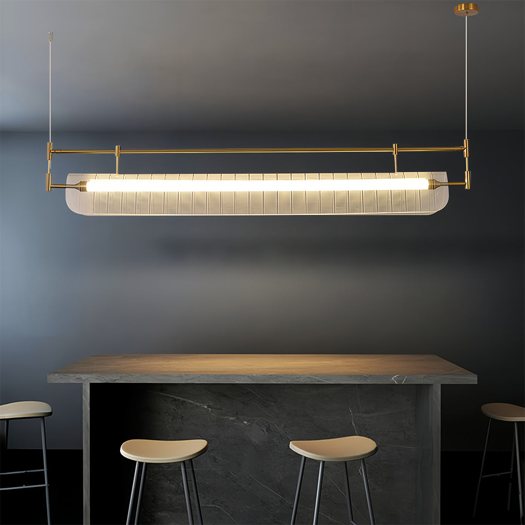 Linear light pendant installed above modern kitchen counter with dark walls and minimalist bar stools.