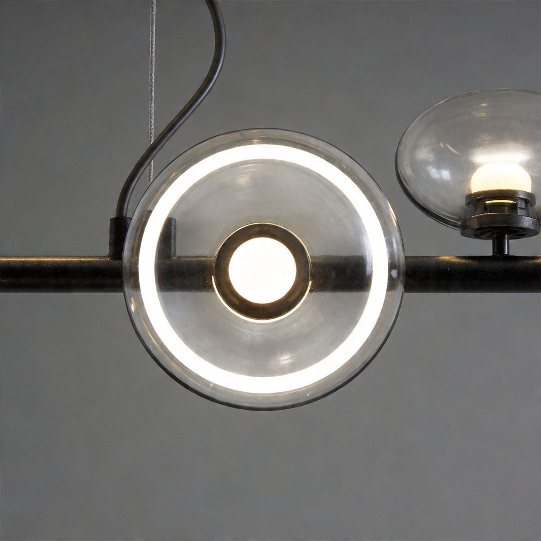 Close-up detail of linear modern chandelier with circular glass light elements and metallic bar frame.