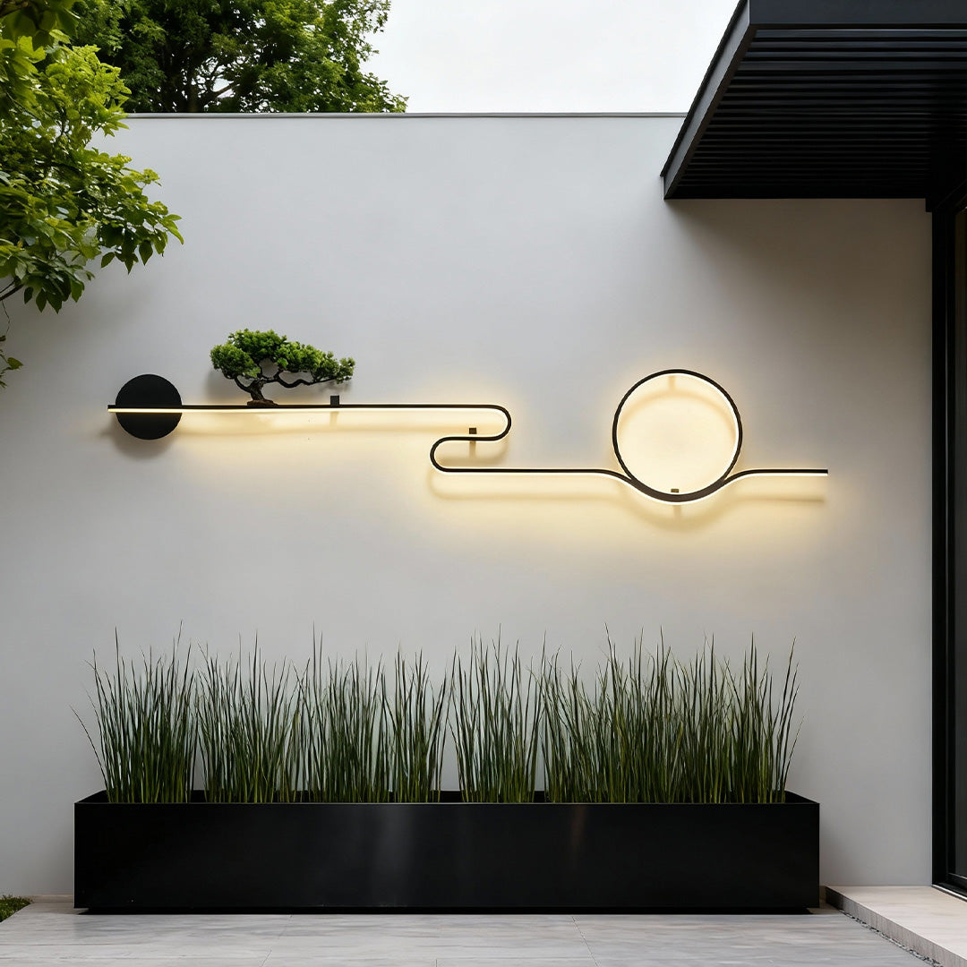 Linear outdoor wall lights with round LED accent installed along a landscaped exterior wall.