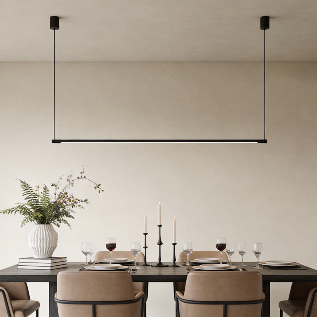 Linear pendant light fixture hanging over long dining table in modern dining room.