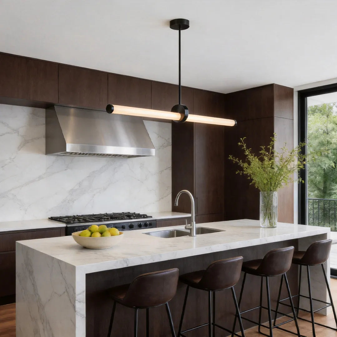 Linear pendant lights illuminating a contemporary marble kitchen island with bar seating.