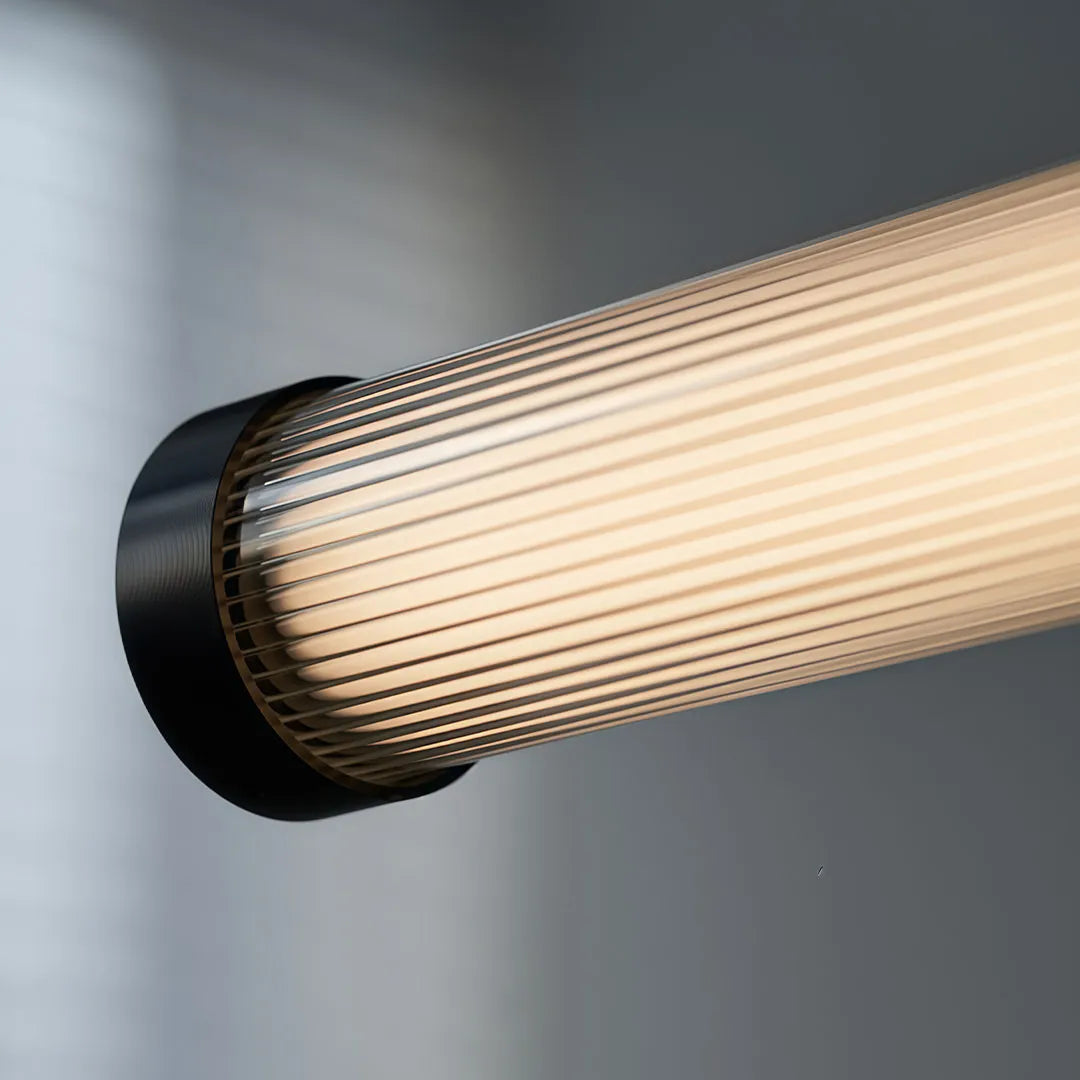 Close-up of linear pendant lights featuring a ribbed tube shade and black end cap.