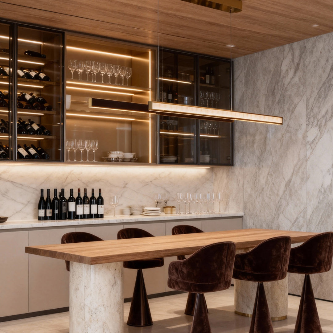 Long gold linear suspension chandelier installed above a kitchen island with marble accents.