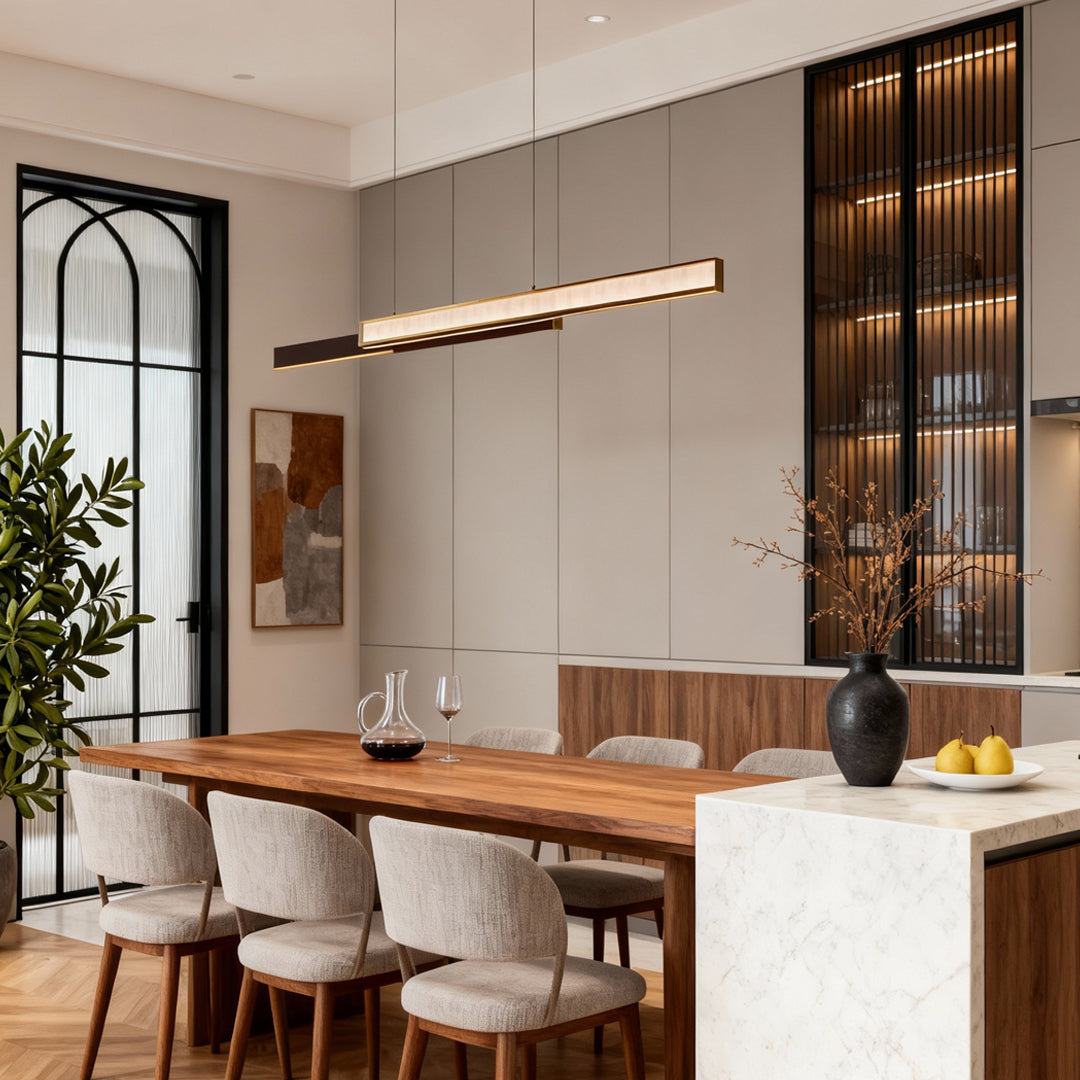 Minimalist linear suspension light in a modern dining area with neutral tones and stone textures.