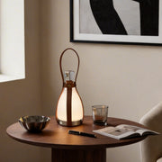Liquor bottle lights with a leather handle, providing warm illumination on a wooden table.
