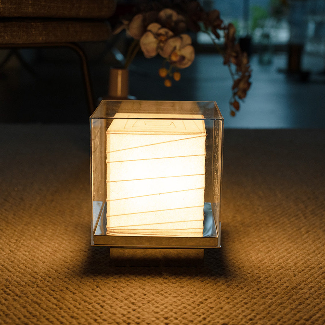 Contemporary Japanese Paper Table Lamp glowing warmly in a living room at night.