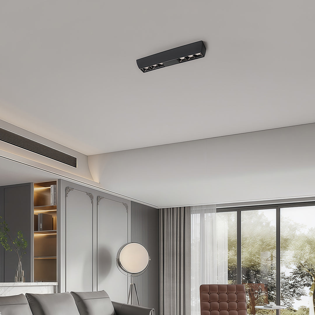 Long black multi-light square downlights fixture installed on the ceiling of a contemporary living room.