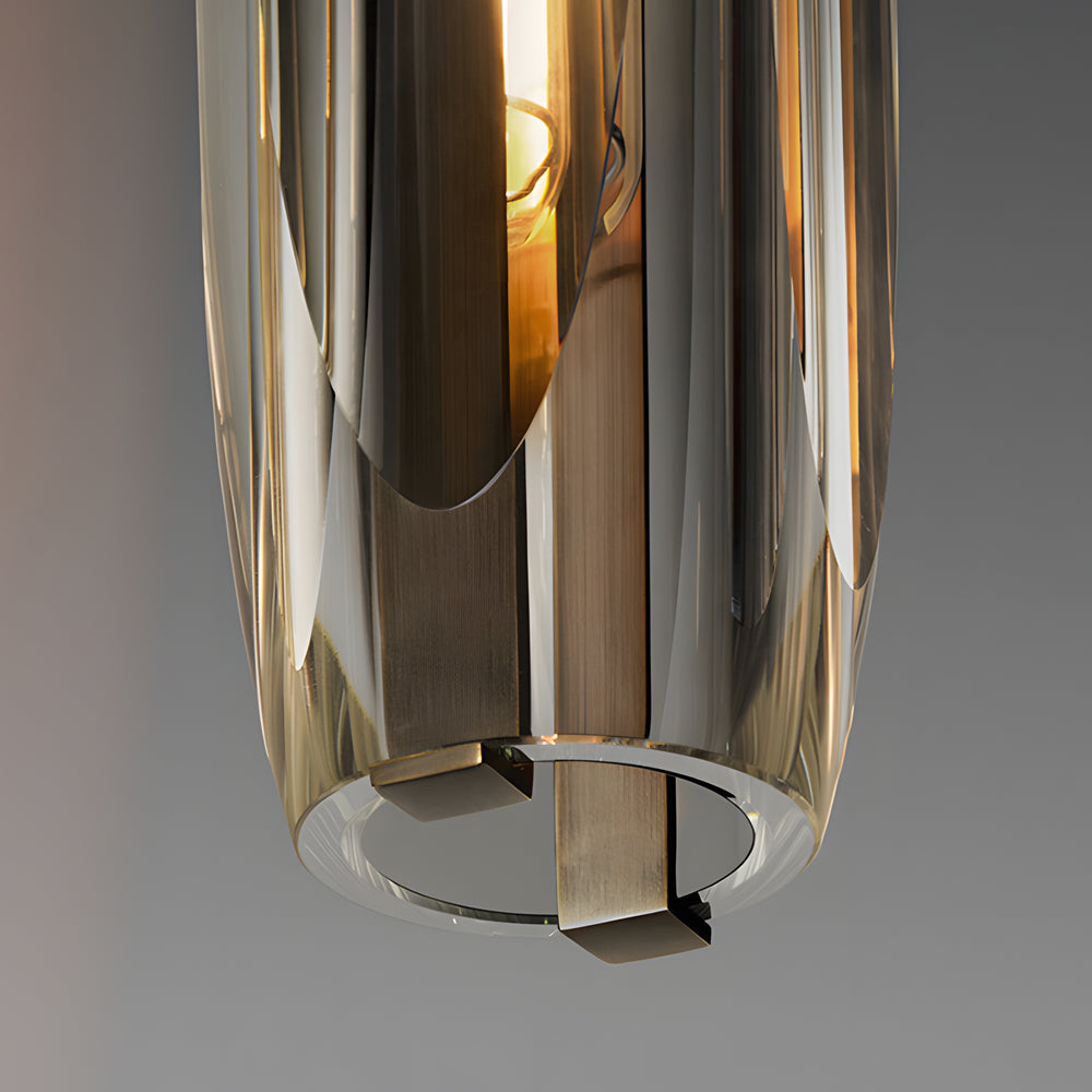 Close-up detail of a long crystal pendant light showing the polished cylindrical shade and inner warm light source.