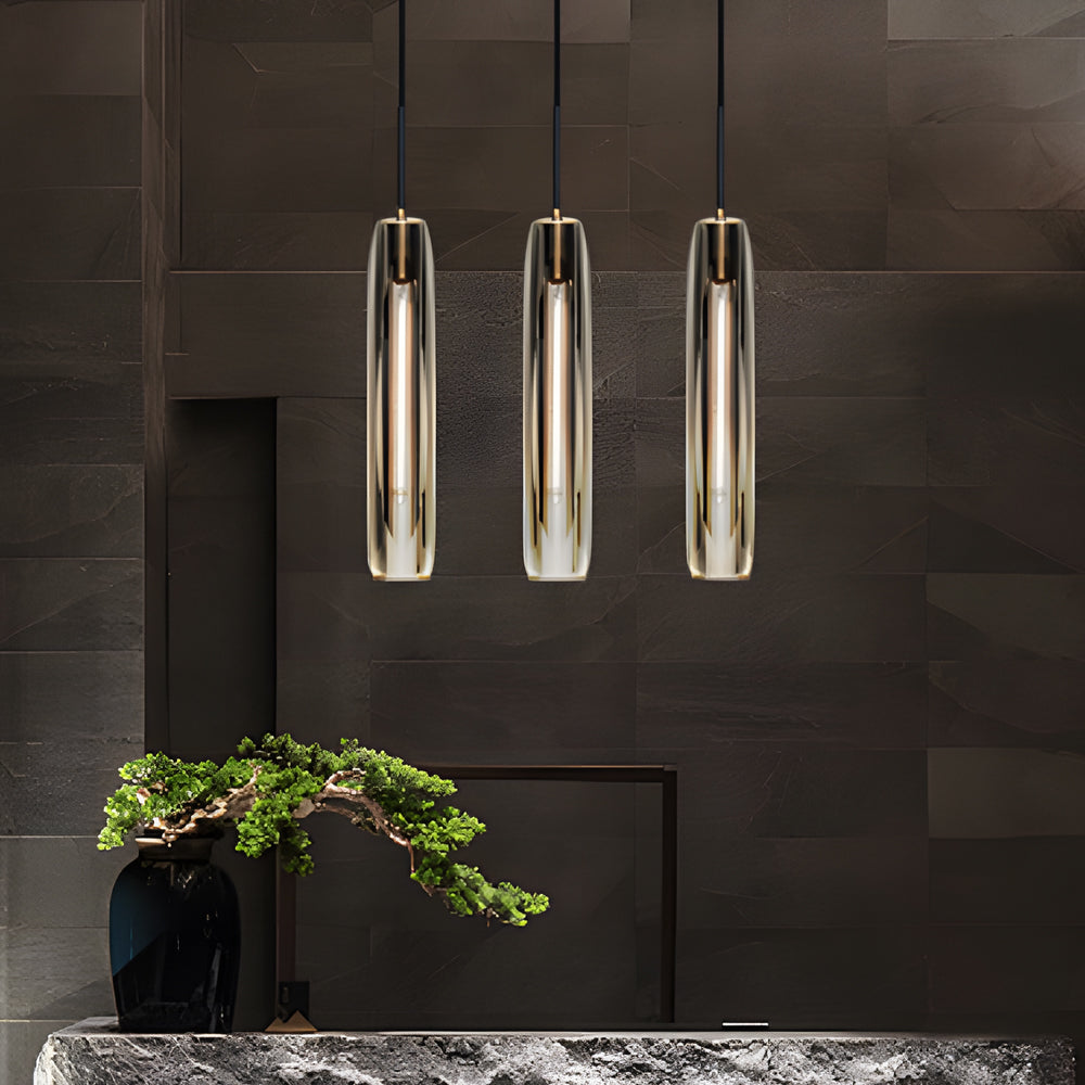 Long crystal pendant lights in a three-light arrangement above a dark modern counter with a warm ambient glow.