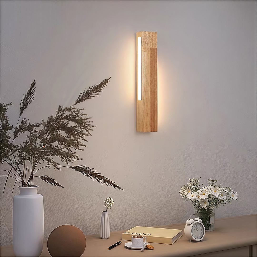 Long, linear Japanese wall light casting a warm glow on a wall above a desk, emphasizing its simple, clean design.