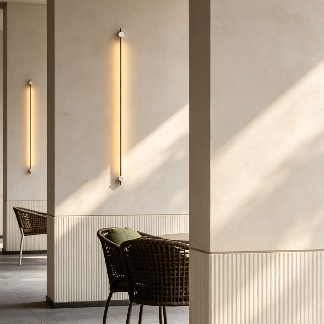Contemporary long linear wall sconce illuminating minimalist lounge area with sleek vertical LED design.