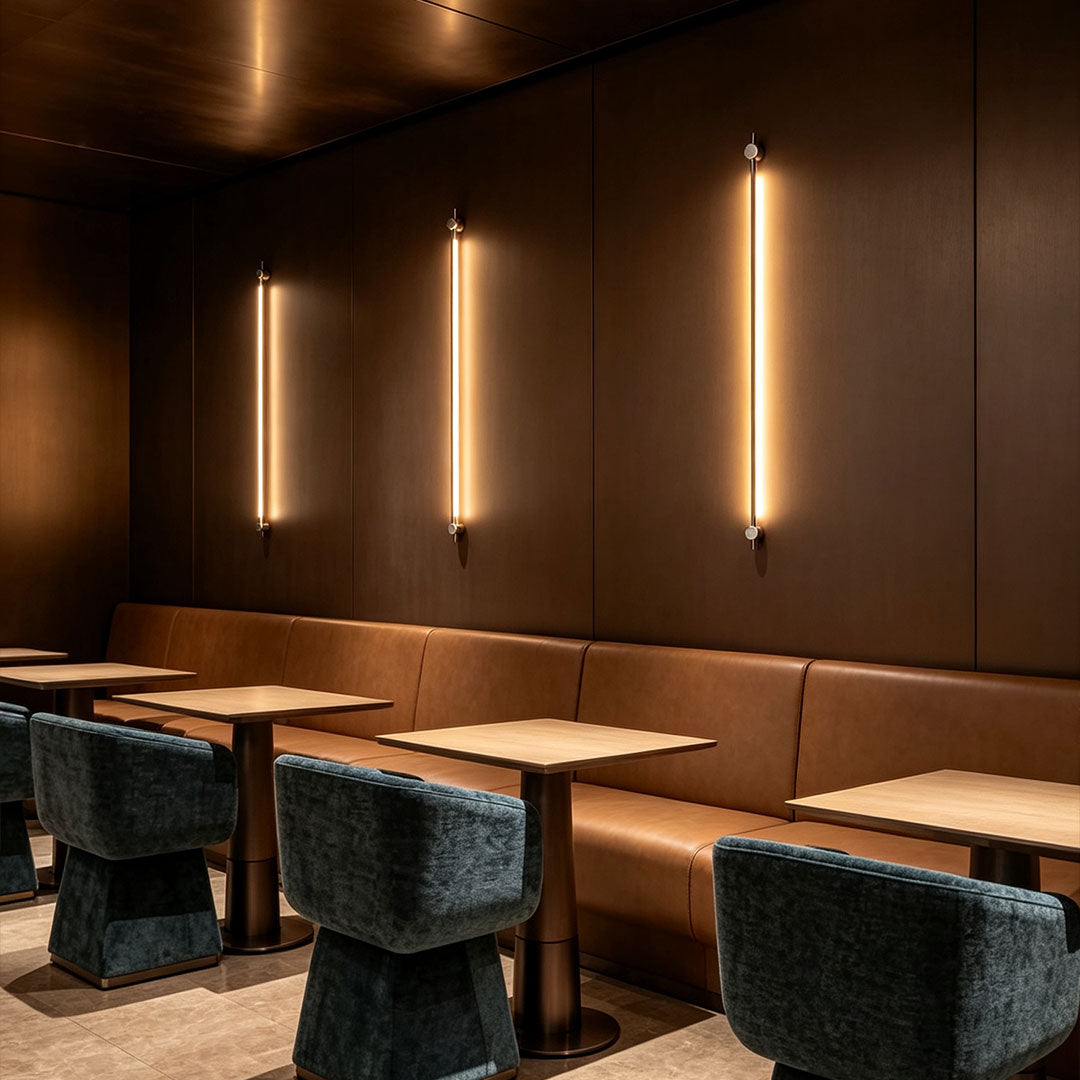 Elegant long linear wall sconce featured in restaurant seating area with warm vertical LED glow.