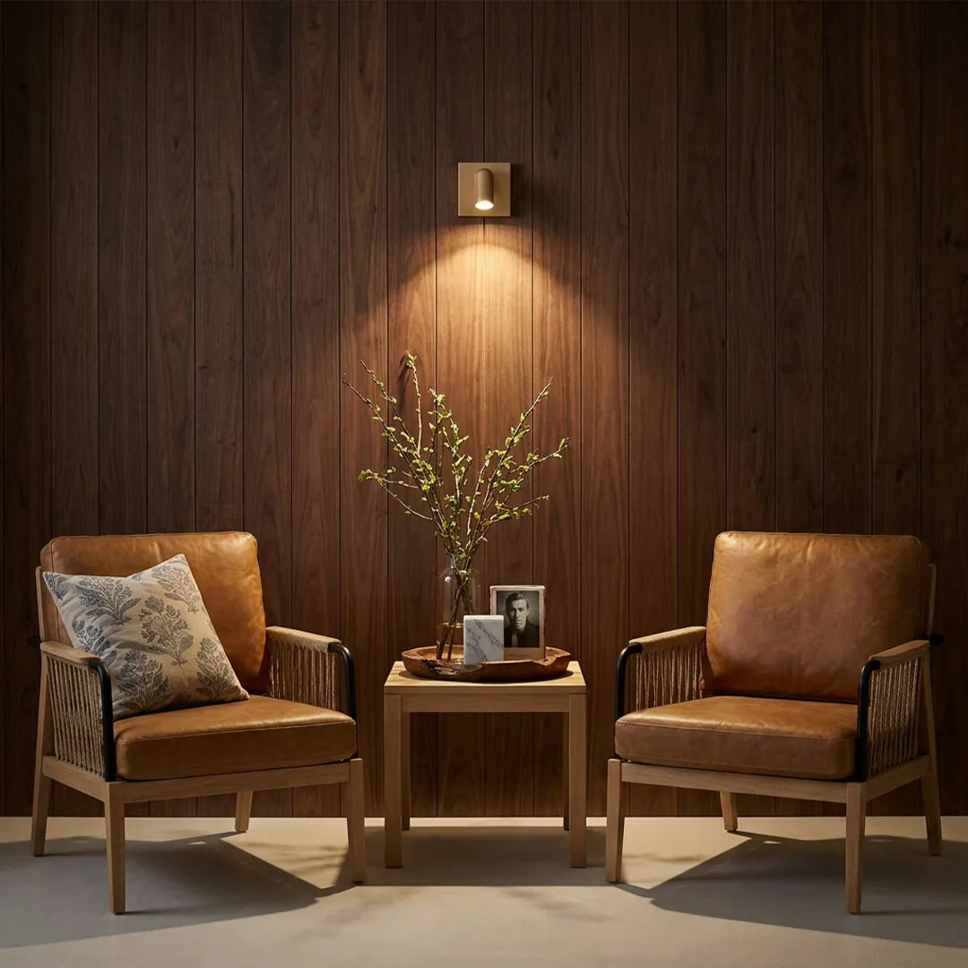 Wall mounted LED reading light casting a focused beam above a side table and lounge chairs.
