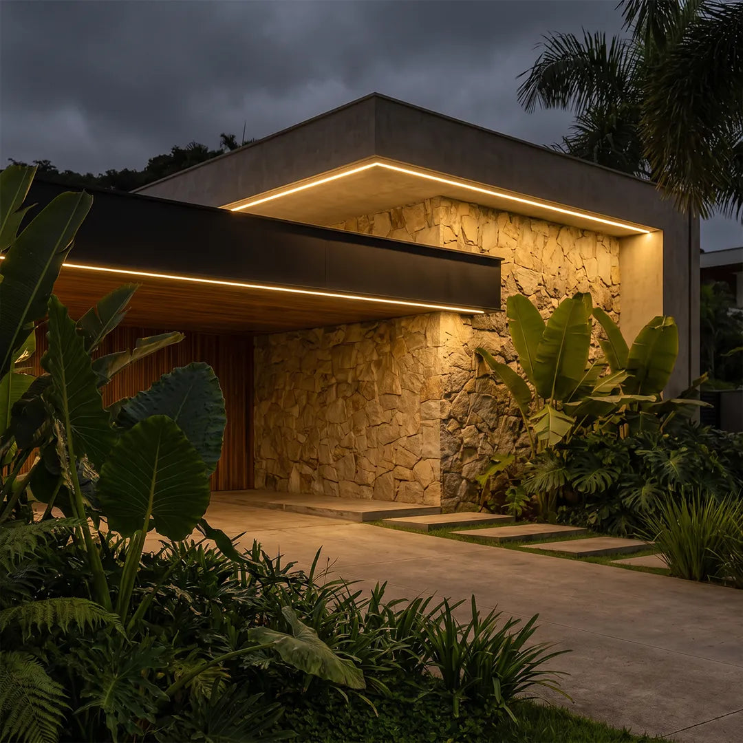 Low voltage wall wash light creating warm illumination on a stone exterior wall and garden area.