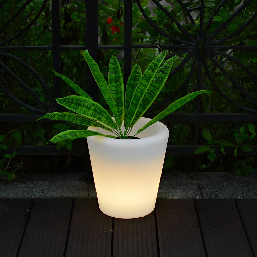 Luminous flower pots casting a warm glow on a wooden deck with lush green plants.