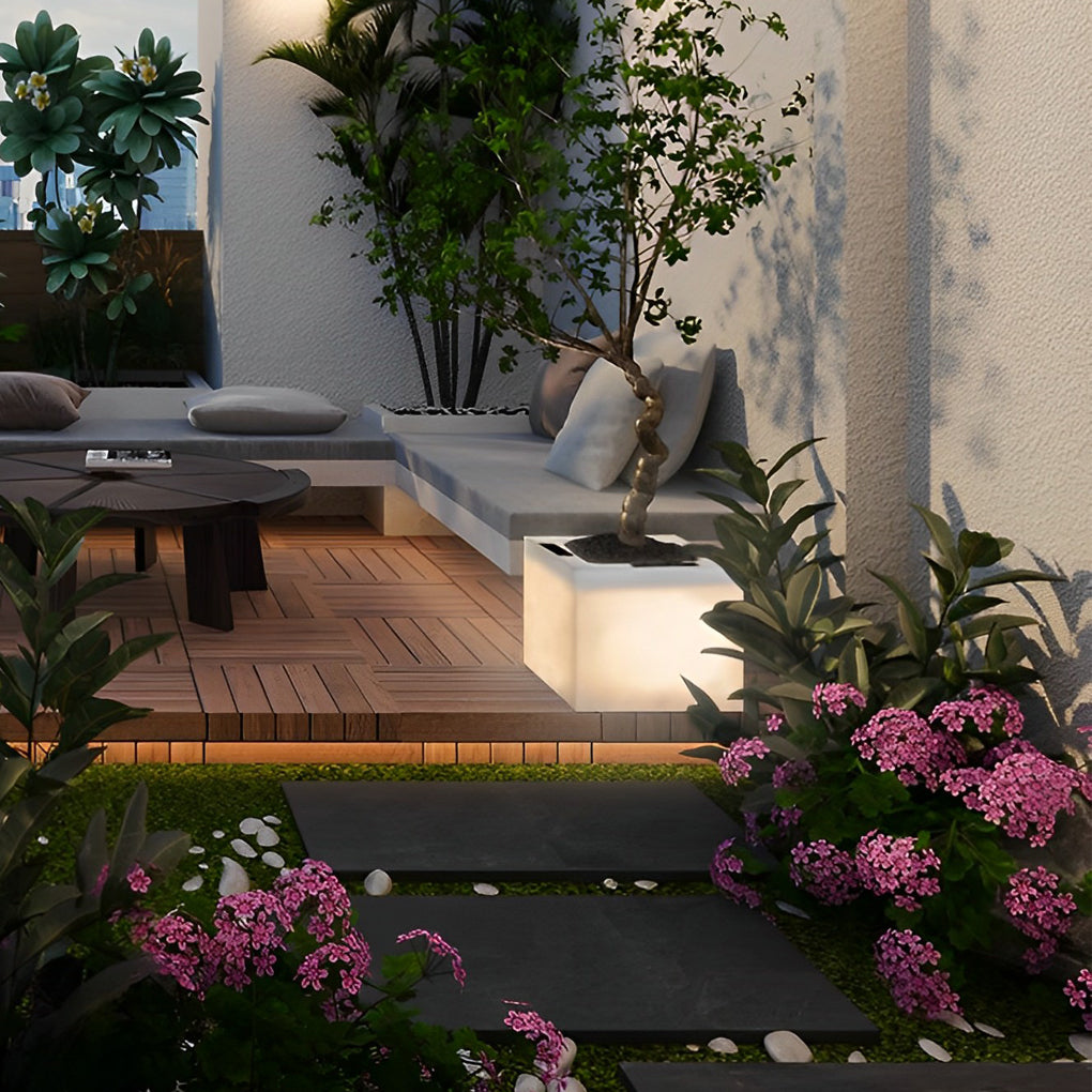 Luminous flower pots with a white finish, providing elegant lighting in a garden.