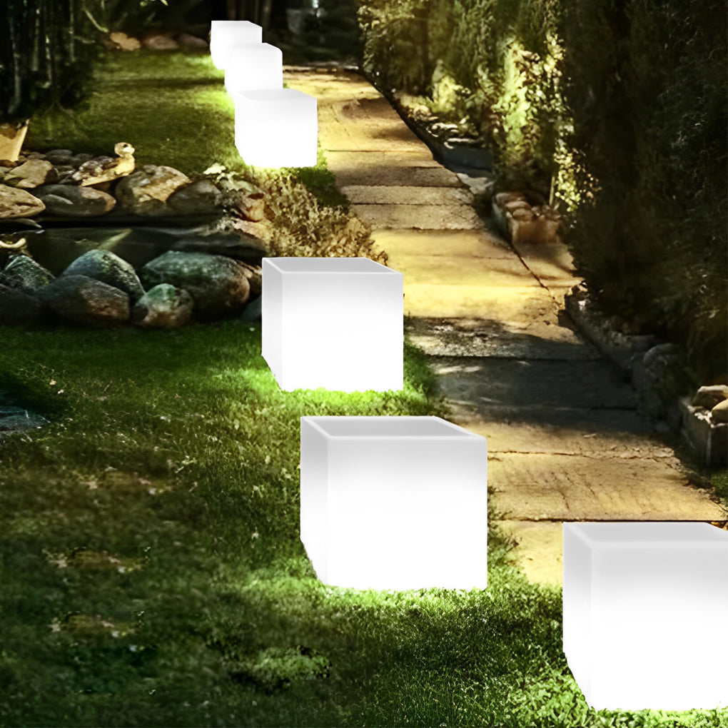 Luminous flower pots with a white finish, glowing near a modern house entrance.