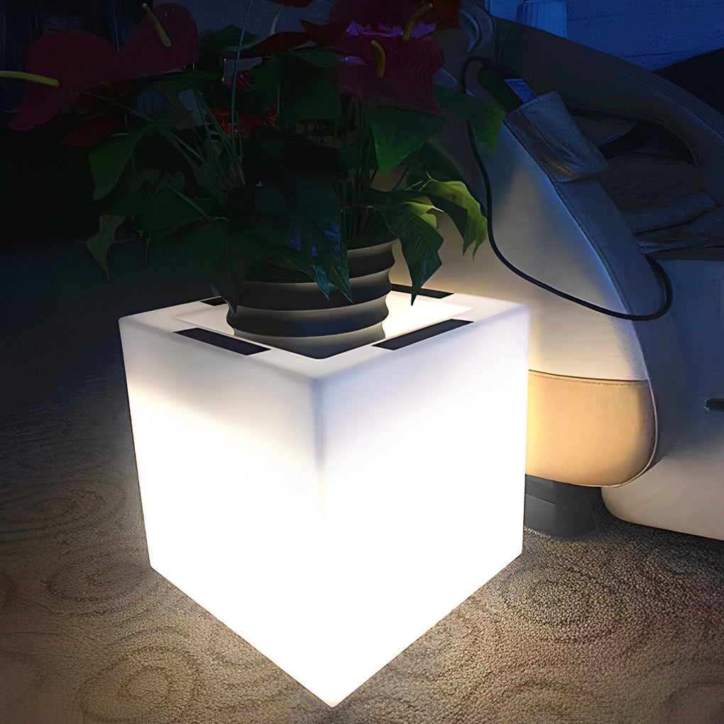 Luminous flower pots with a white finish, providing warm light near a garden.