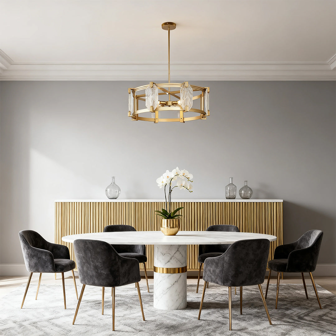 Luxurious round glass chandelier with a geometric gold frame, centered above a white marble dining table in a sophisticated gray room.
