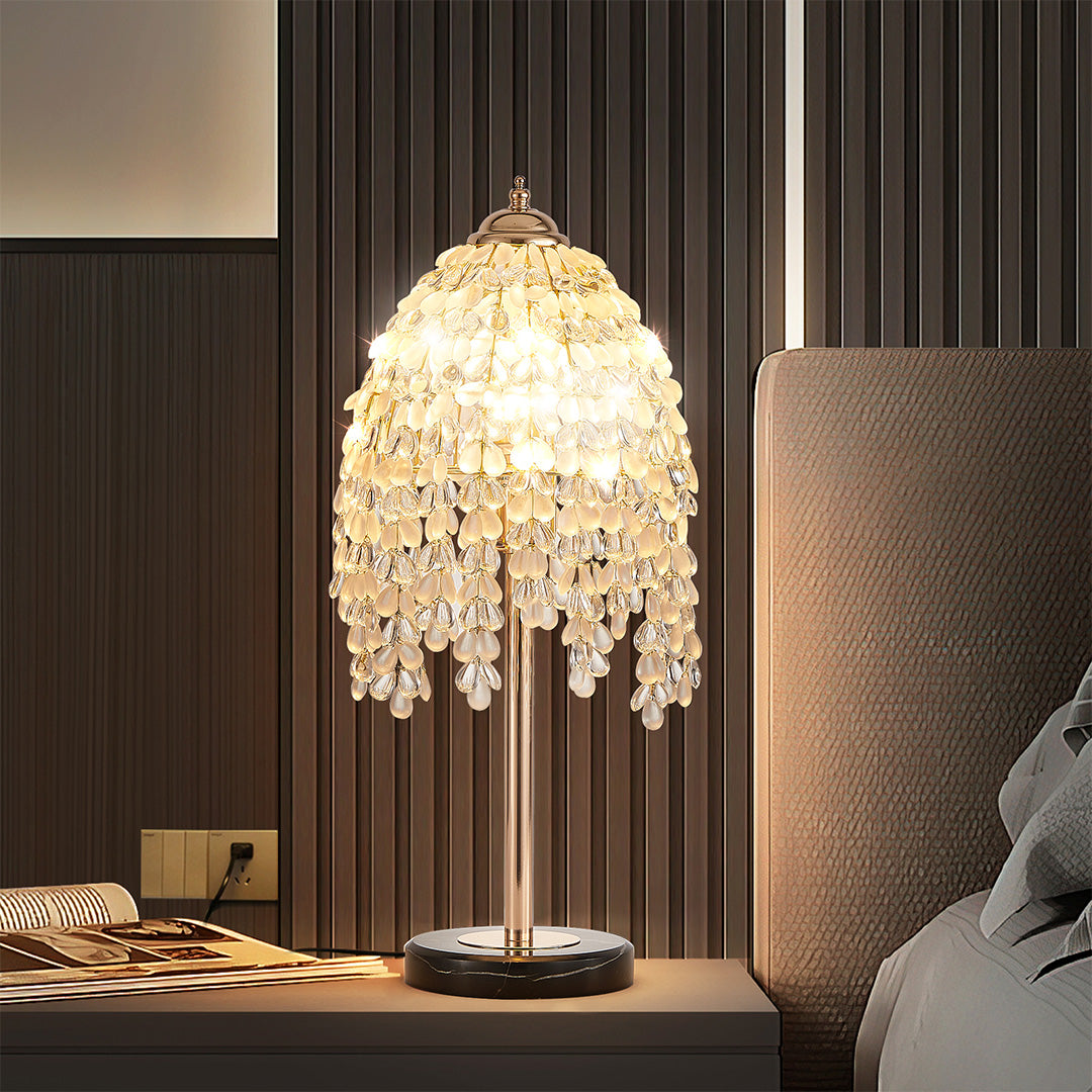 Luxurious gold bedside table lamp featuring glass shade chandelier aesthetic with tiered crystal droplets in modern dark bedroom.