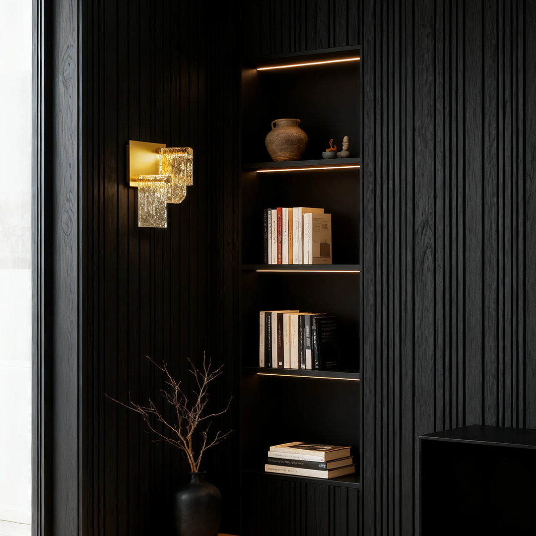 Luxurious gold wall light casting warm glow in dark sophisticated study with built-in shelving
