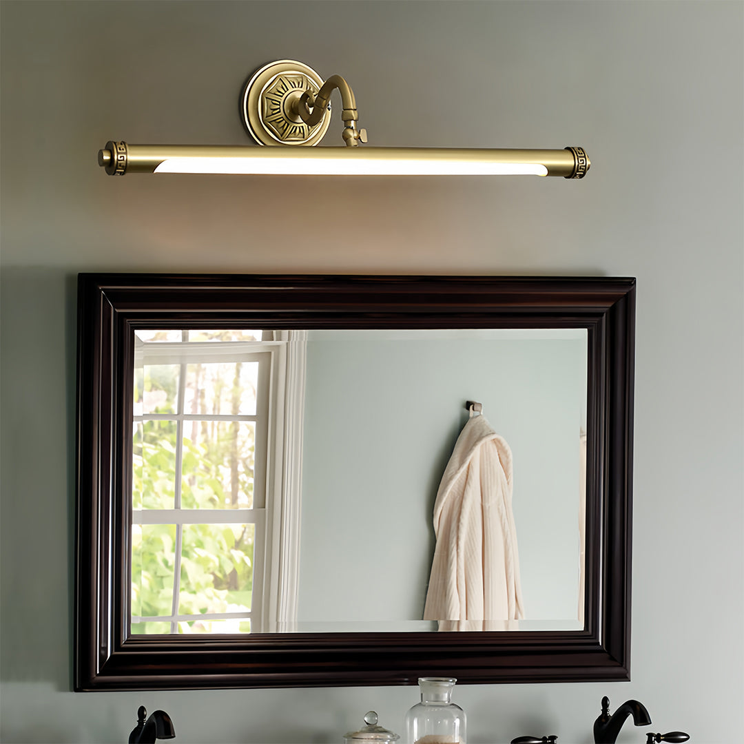 Gold bathroom vanity light mounted above mirror in luxurious bathroom with marble surfaces