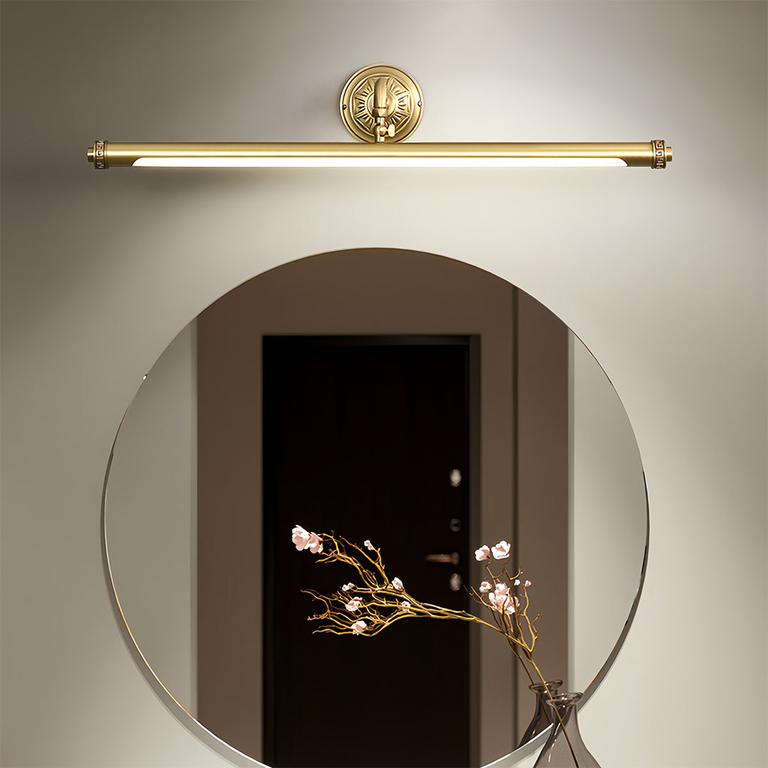 Gold bathroom vanity light mounted above mirror in luxurious bathroom with marble surfaces