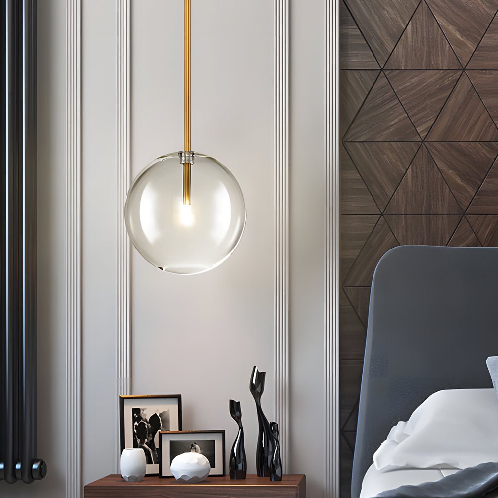 Clear glass globe pendant light with gold details, offering a refined touch of modern luxury to any interior design.