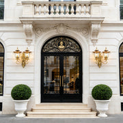 Luxury mansion entrance featuring elegant Copper Outdoor Wall Sconces beside ornate black double doors and stone facade.