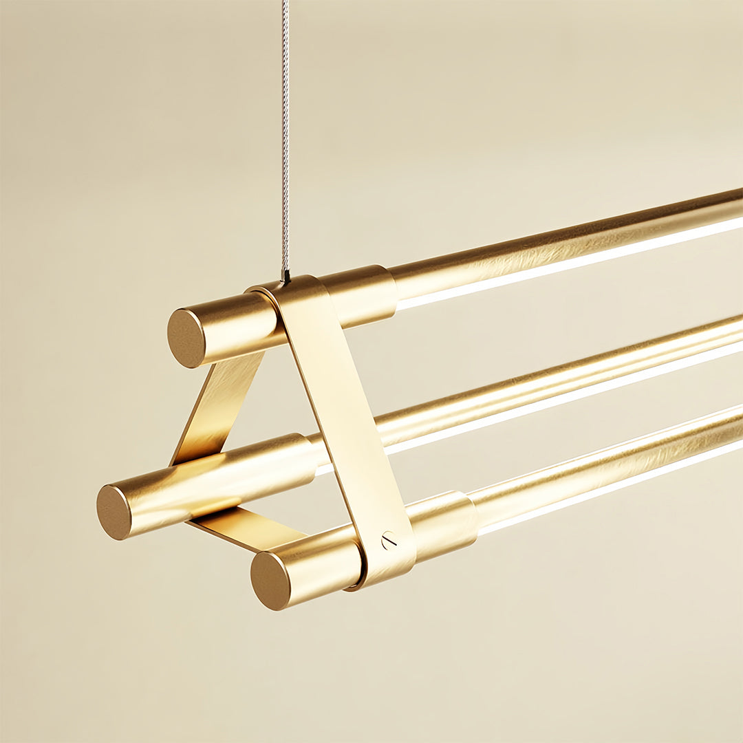 Luxury linear pendant lights with golden finish suspended over marble surface in upscale interior