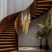 Amber glass stairway chandelier hanging above curved wooden staircase.