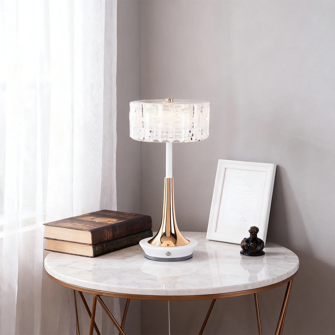 Luxury style cordless mushroom table lamp with crystal shade and gold base, placed on a marble-top end table with decor. 