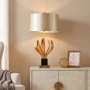 Luxury vintage metal table lamps with gold leaf base and black pedestal on a white sideboard.