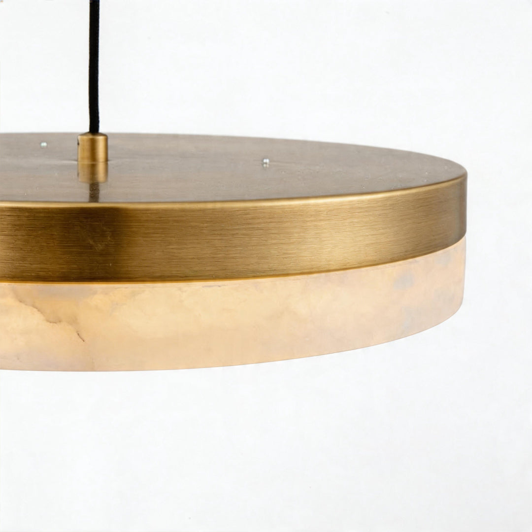 Macro detail of the brushed brass band and marble shade on a modern disc pendant light fixture