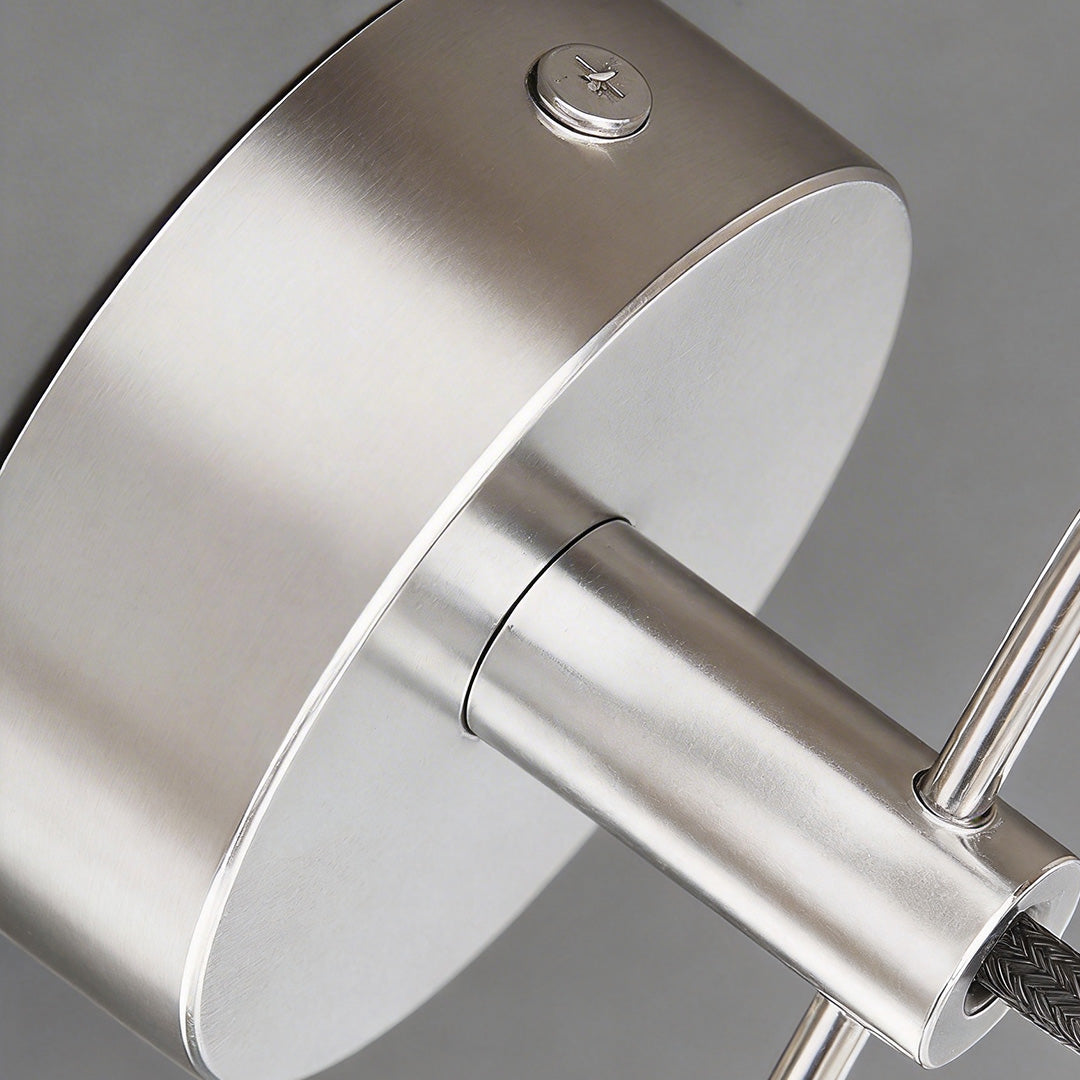 Macro detail of the brushed nickel backplate for industrial wall lights with mounting screws.