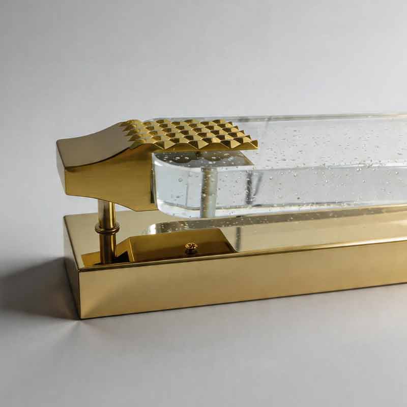 Macro detail of luxury modern wall lights with gold textured end caps and seeded crystal bar.