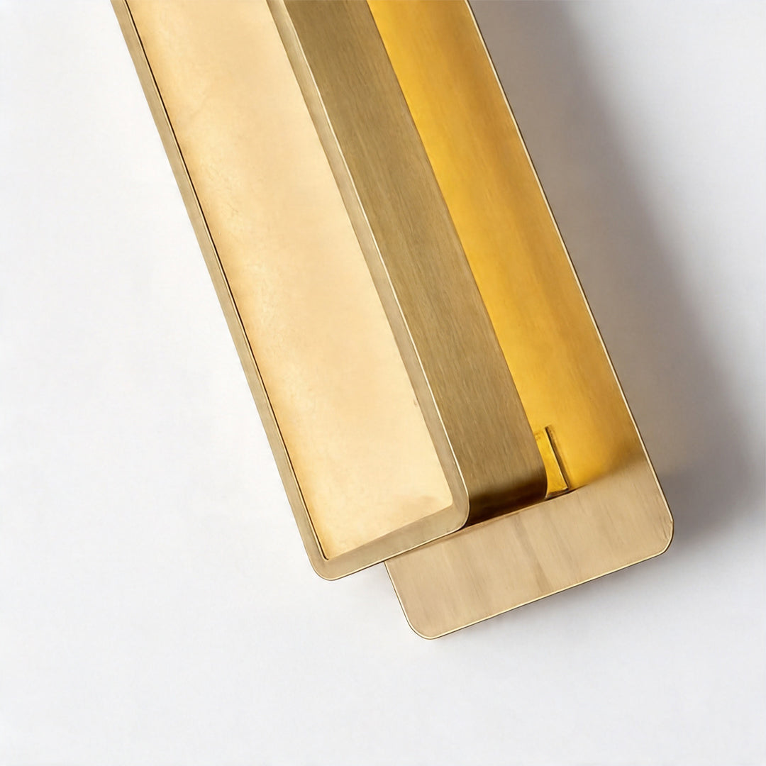 Macro detail of a gold wall light fixture showing the brushed brass finish and internal glow.