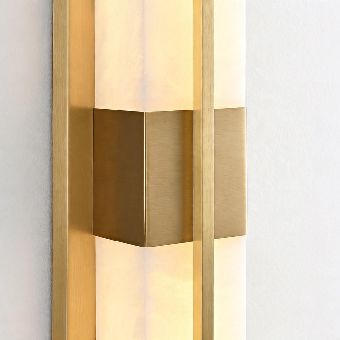 Macro detail of a gold wall lighting fixture showing brushed metal finish and marble texture.
