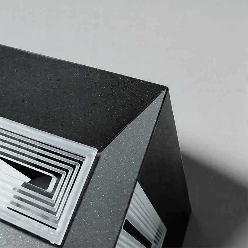 Macro detail of square pillar lights showing textured black metal and ribbed glass diffusers.