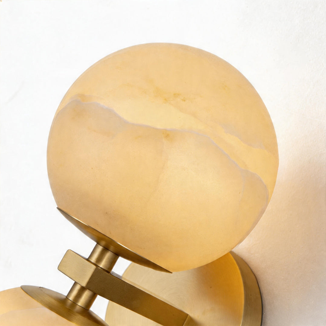 Macro detail of the natural stone texture and warm glow of a double globe wall light fixture.
