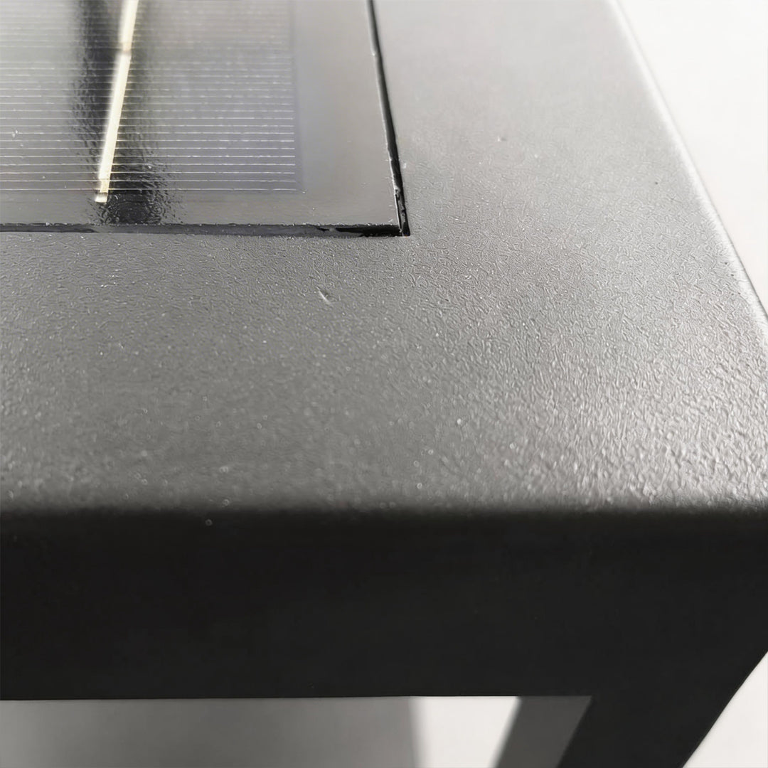 Macro detail of solar panel and matte finish on a durable black outdoor concrete pillar light.