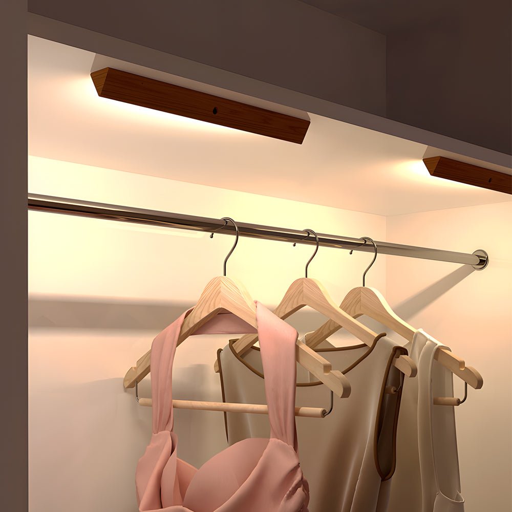 Magnetic motion sensor light illuminating a modern wardrobe with hanging clothes and accessories.