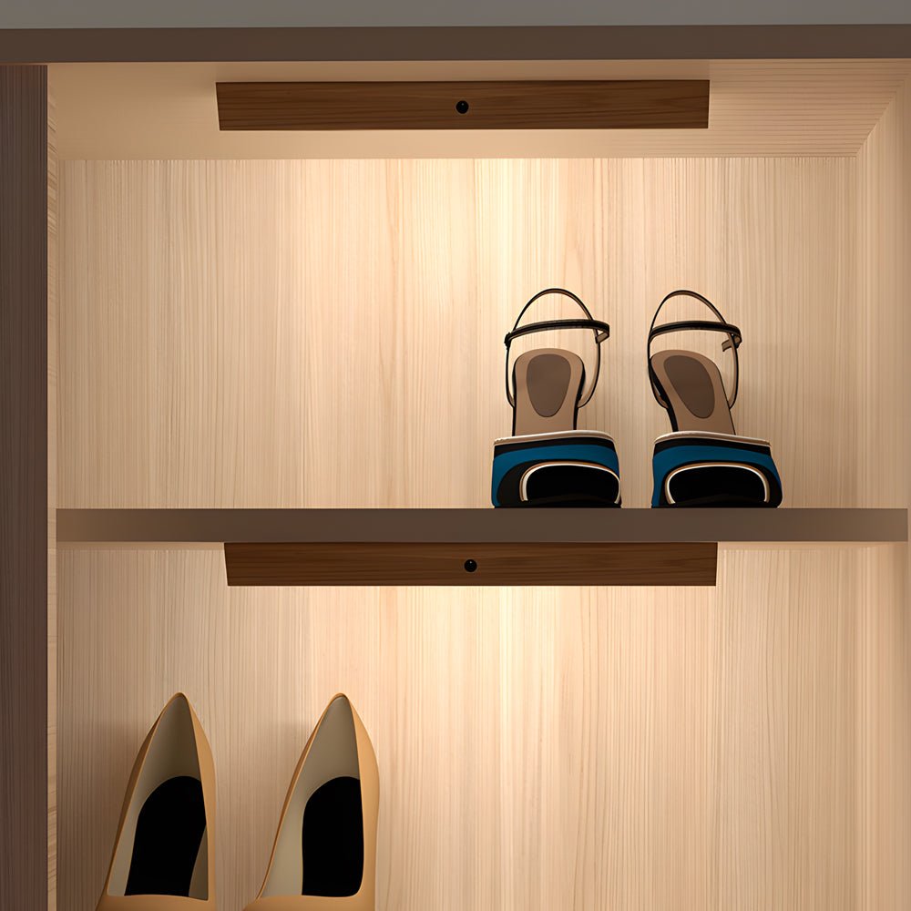 Magnetic motion sensor light providing soft illumination for shoes on a wooden shelf.