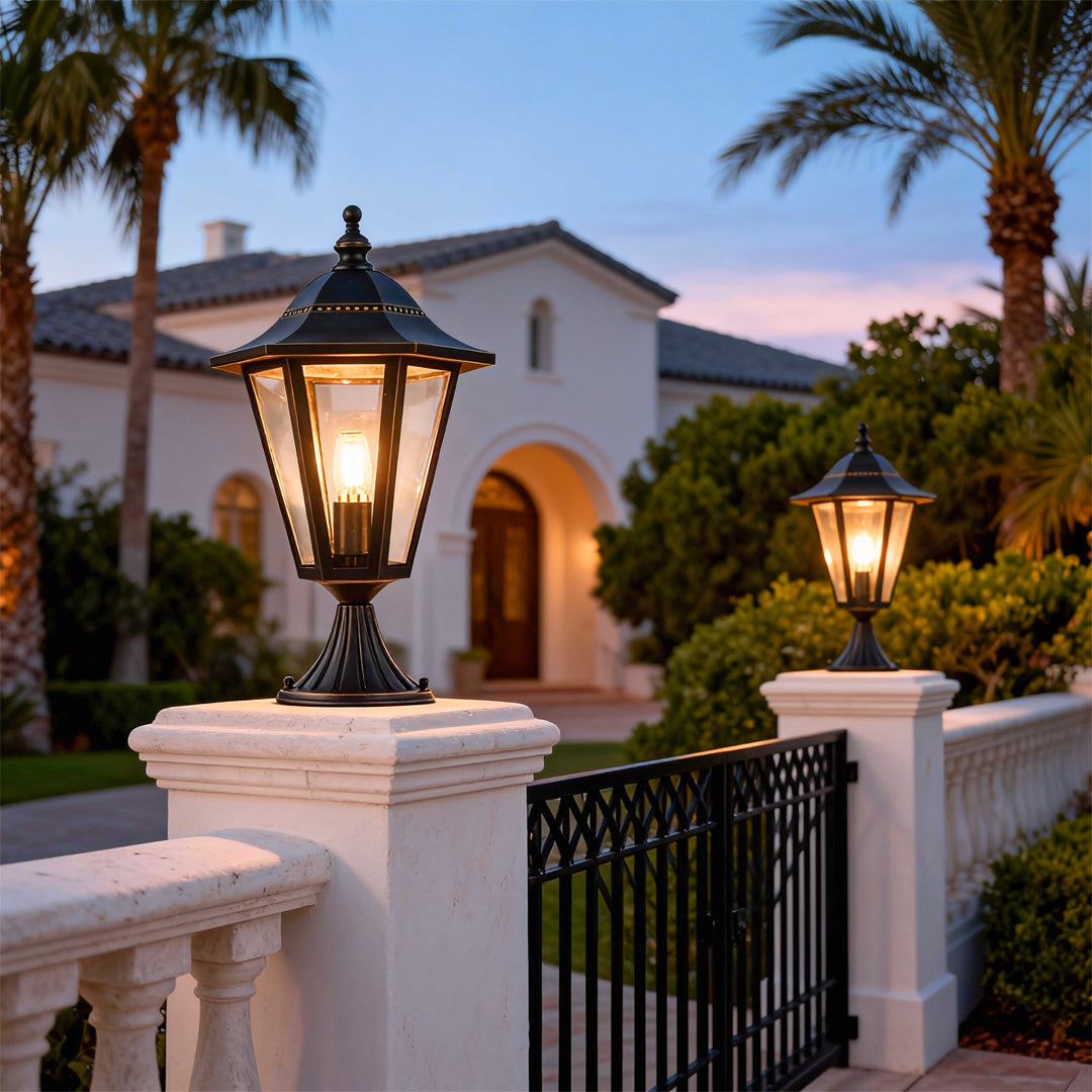 Main gate pillar light casting a warm glow on a white fence and garden pathway.