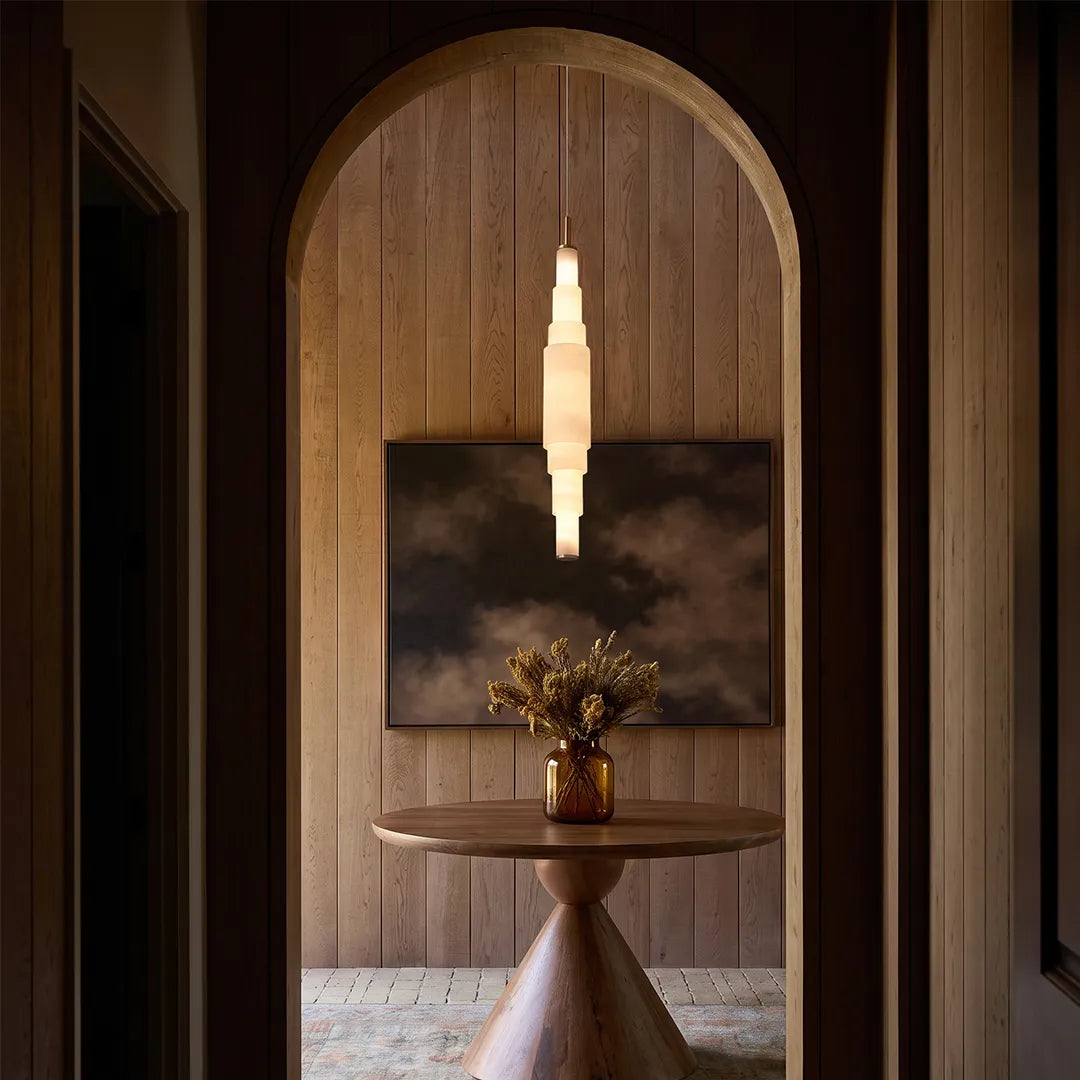 Marble chandelier displayed in an arched hallway with warm wood paneling and a round table.