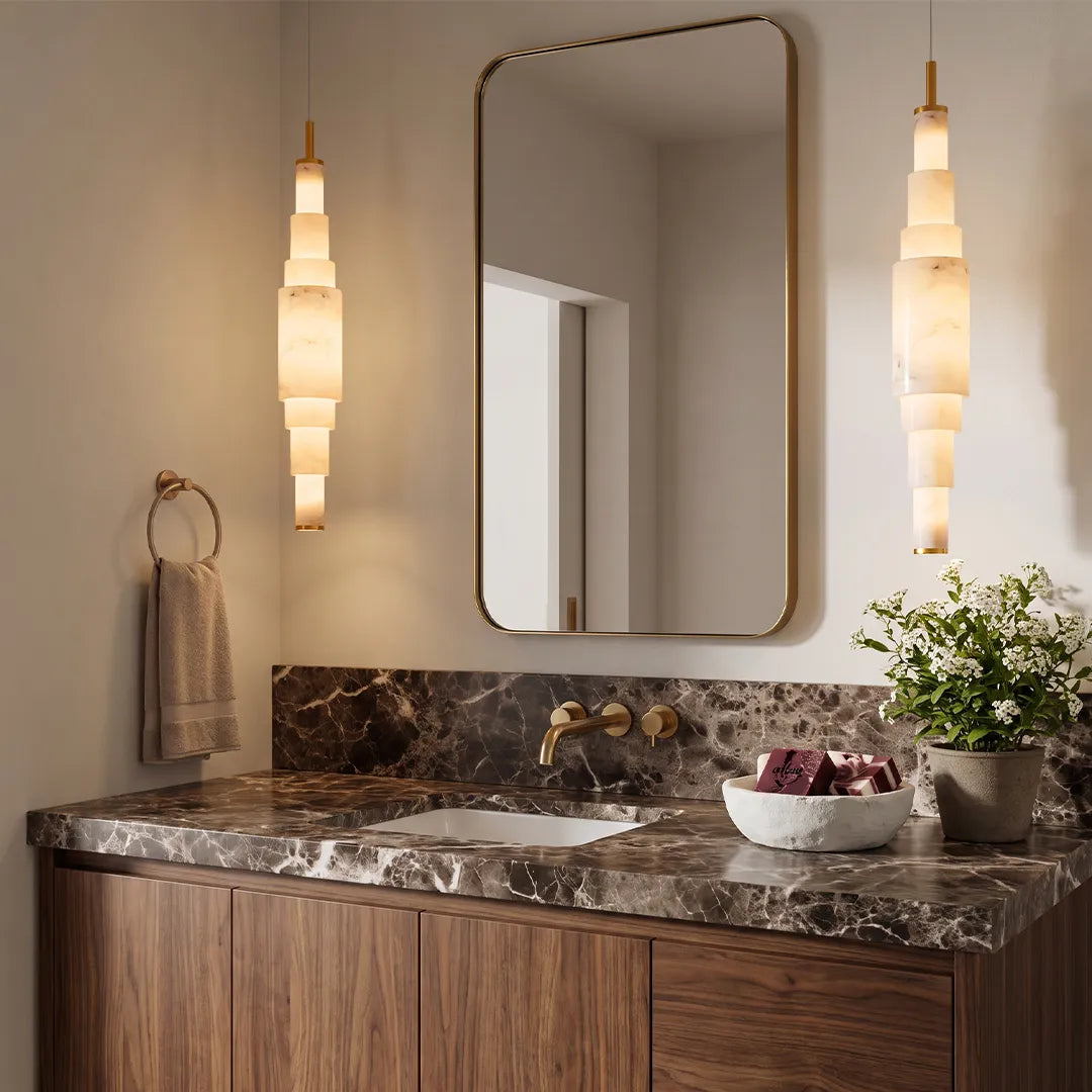 Marble chandelier installed beside a vanity mirror in a bathroom with dark marble countertops.