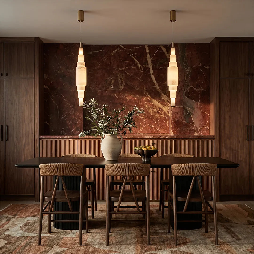 Marble chandelier hanging above a dining table in a modern dining room with a stone feature wall.