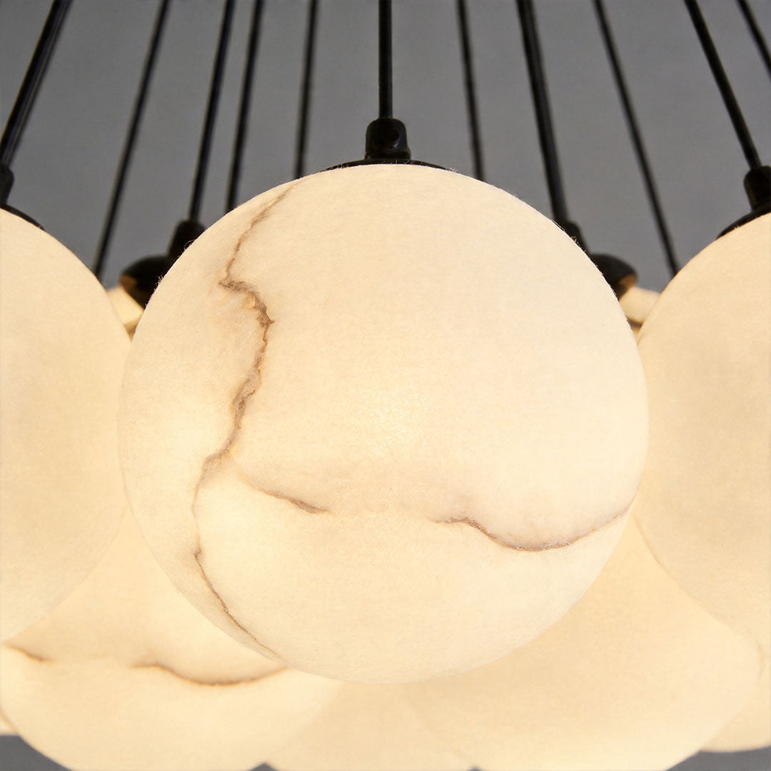 Detailed view of marble-style glass globes on matte black chandelier with warm light effect.