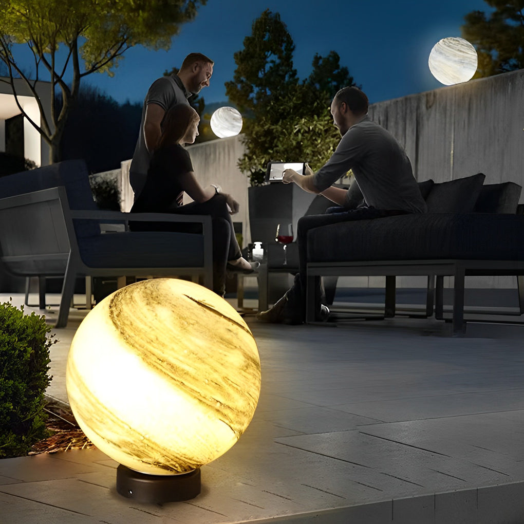Globe pillar lights with marble texture beside modern house at night.