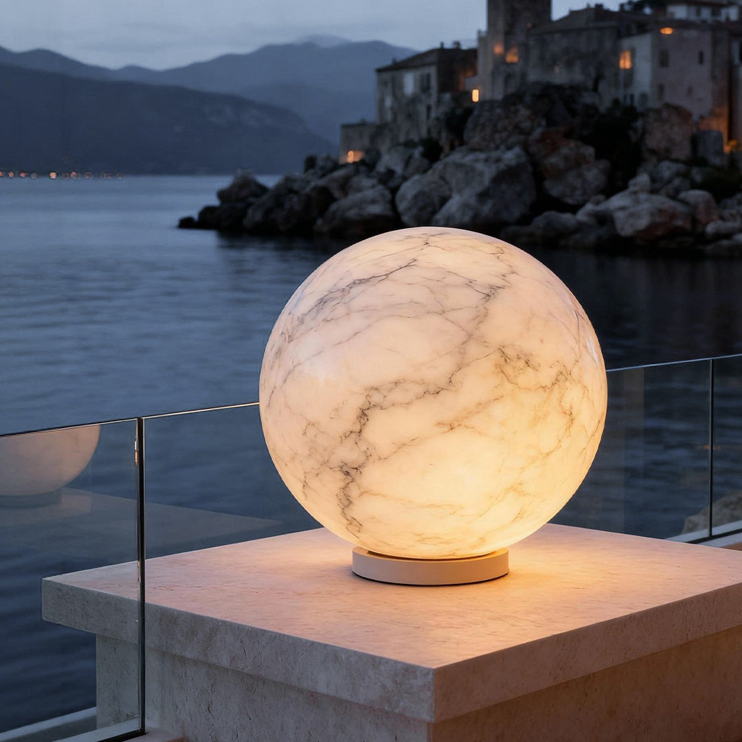 Marble-textured outdoor pillar light on a stone pillar, providing warm illumination near a seaside balcony.